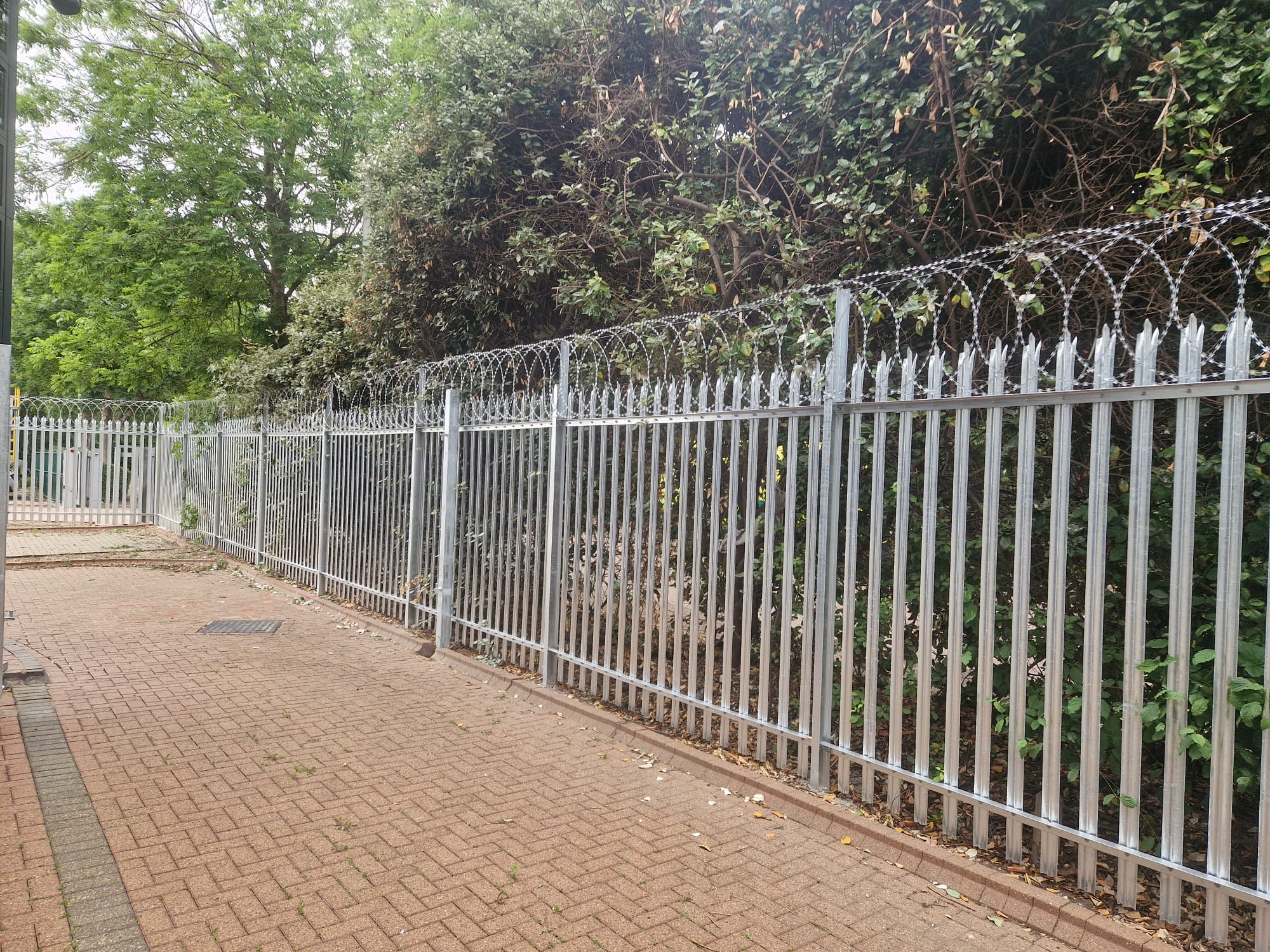 Galvanised palisade fencing topped with razor wire