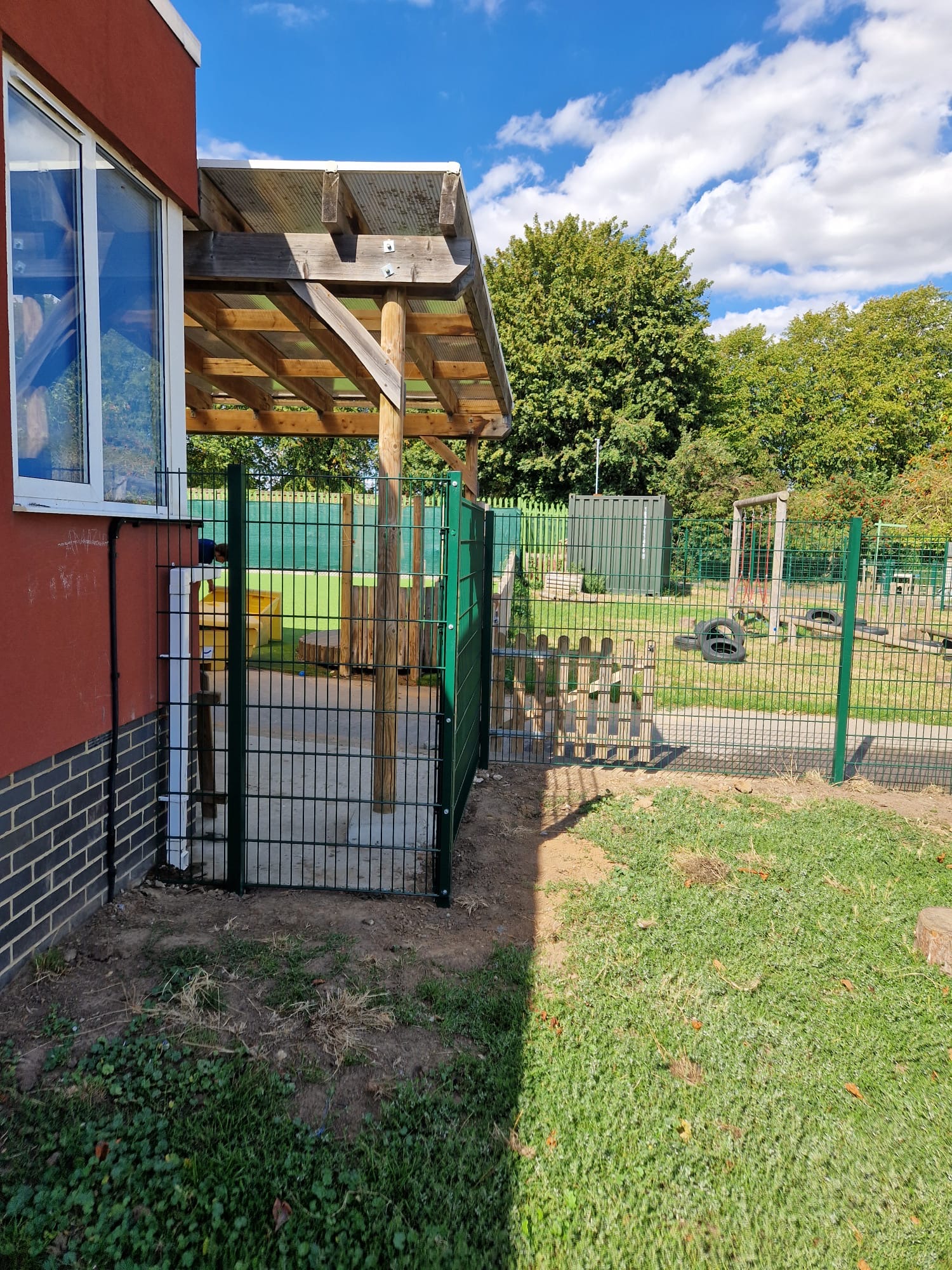 Mesh fencing and pedestrian gate returning against the school building
