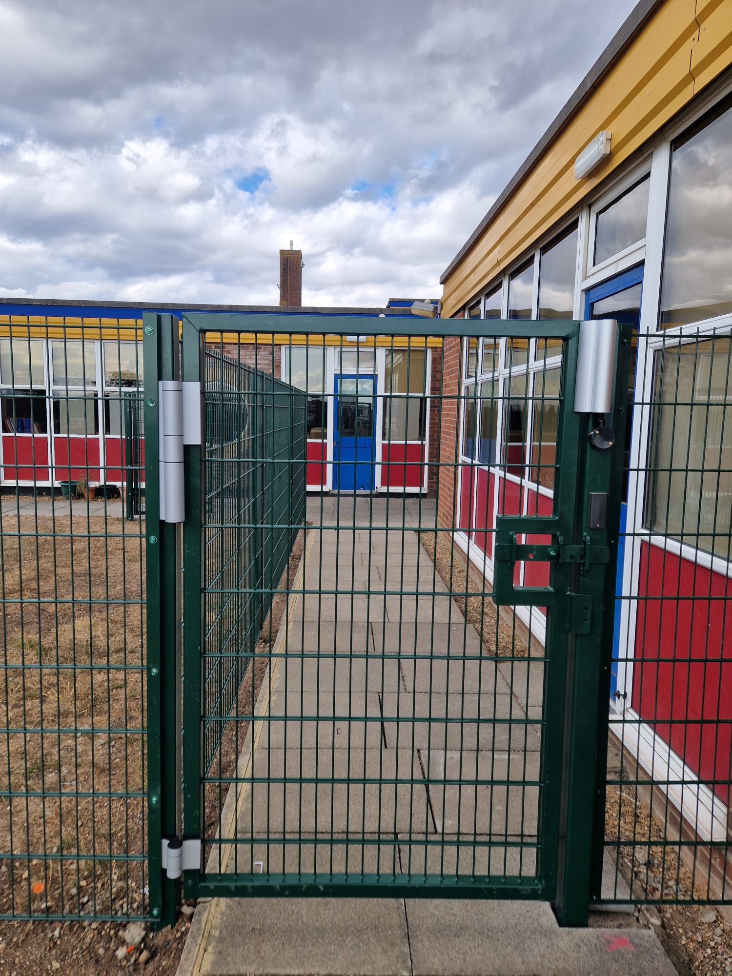 Green mesh pedestrian gate providing controlled access at a school