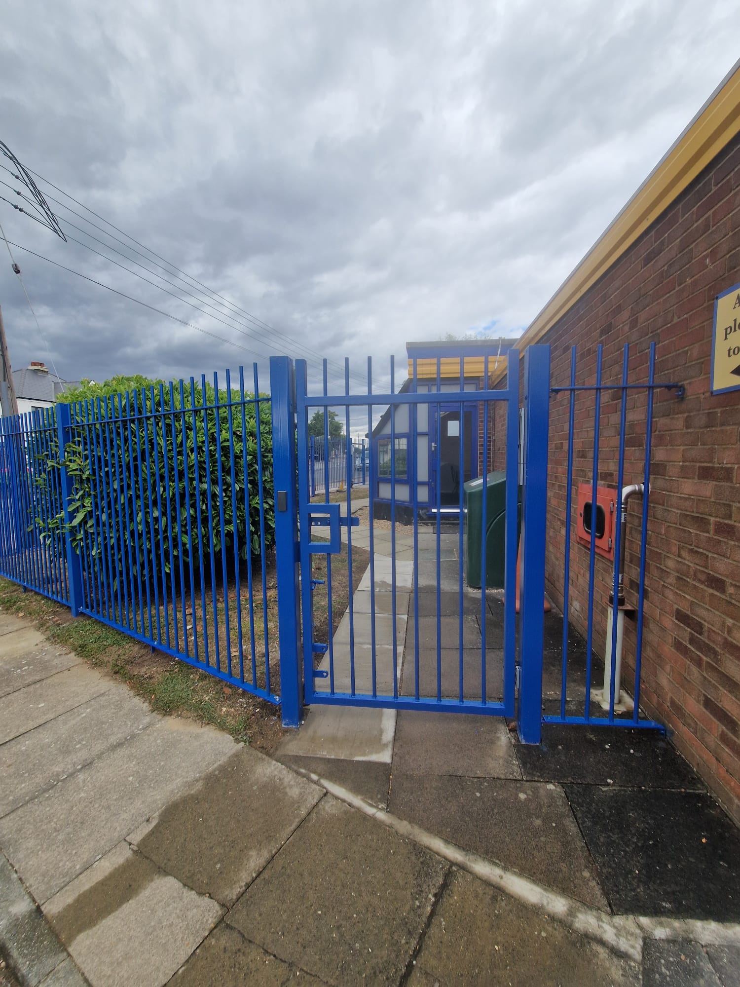 Completed blue pedestrian gate beside the visitor reception sign