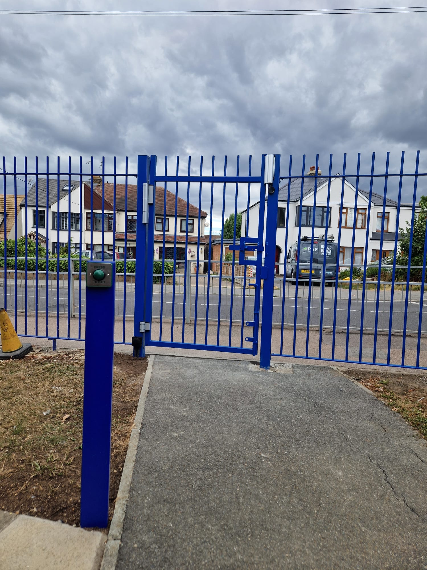 Blue steel pedestrian guard railings and access-controlled gate installed at a commercial site